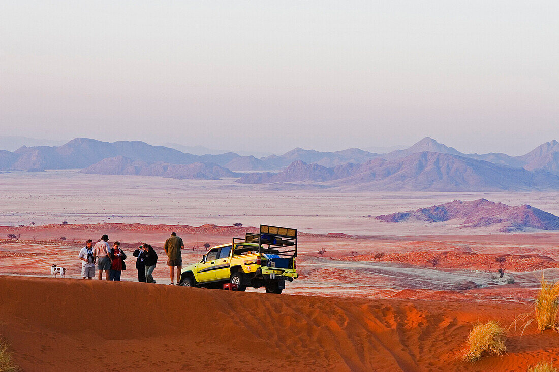 Eine Gruppe Touristen und ein Geländewagen auf einer naturkundlichen Sonnenuntergangs Tour. Gondwana Namib Desert Park. Wüste Namib. Südliches Namibia. Afrika.