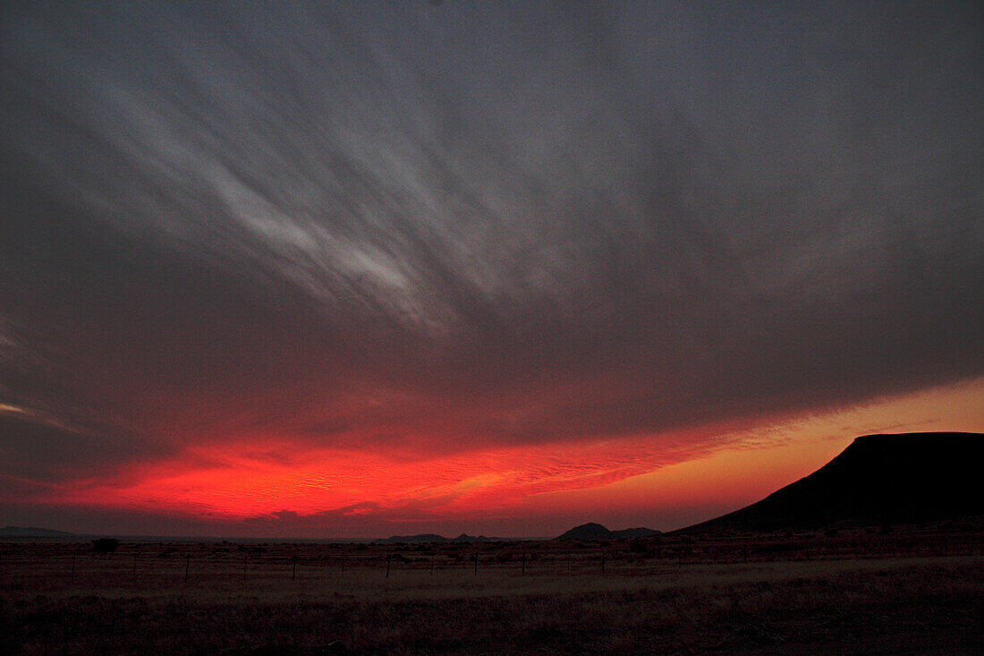 Rot glühende Wolken nach Sonnenuntergang in der Namib Wüste. Südliches Namibia, Afrika.