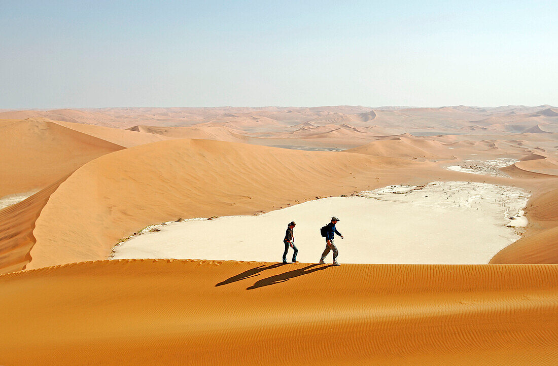 Young couple moving up Big Daddy. one of the earth highest dunes, Sossusvlei. Namib desert. Namibia. Africa