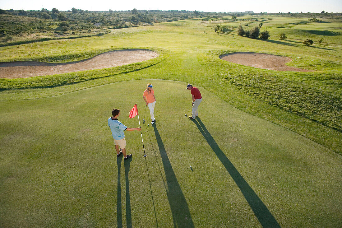 Golfers on golf course, long shadows, Apulia, Italy