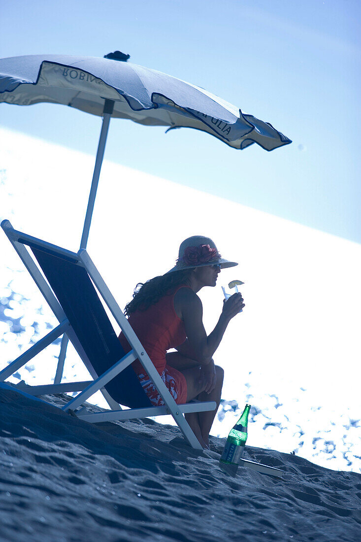 Junge Frau im Liegestuhl am Strand, Apulien, Italien