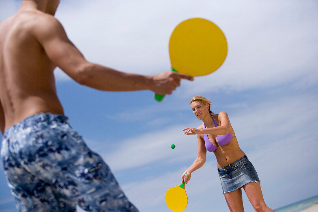Young couple playing paddle ball on beach, Apulia, Italy