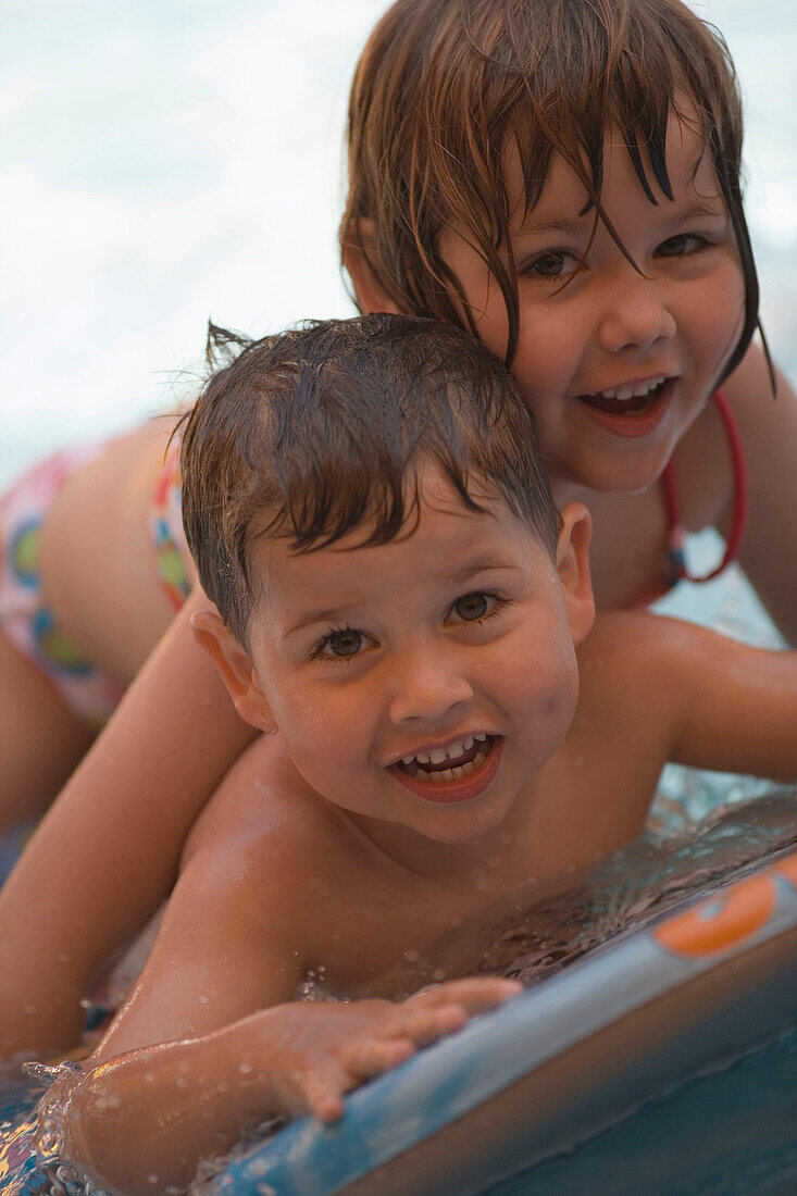 Zwei Kinder spielen im Swimmingpool, Apulien, Italien