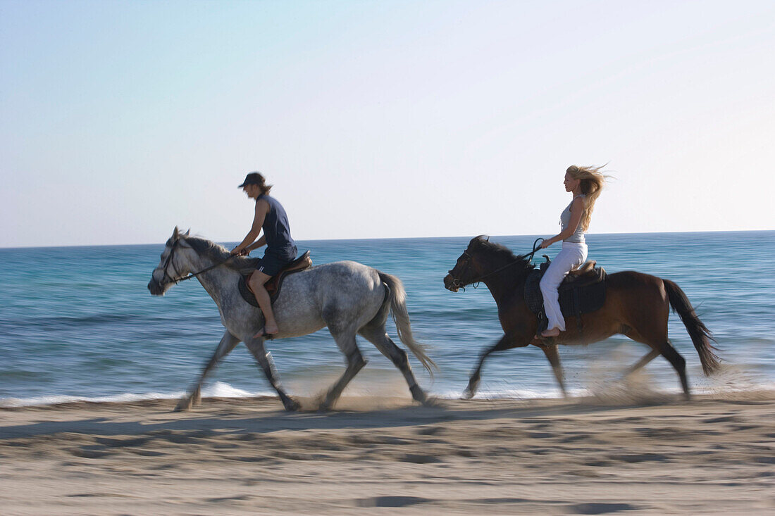 Young couple horseback riding at beach, Apulia, Italy