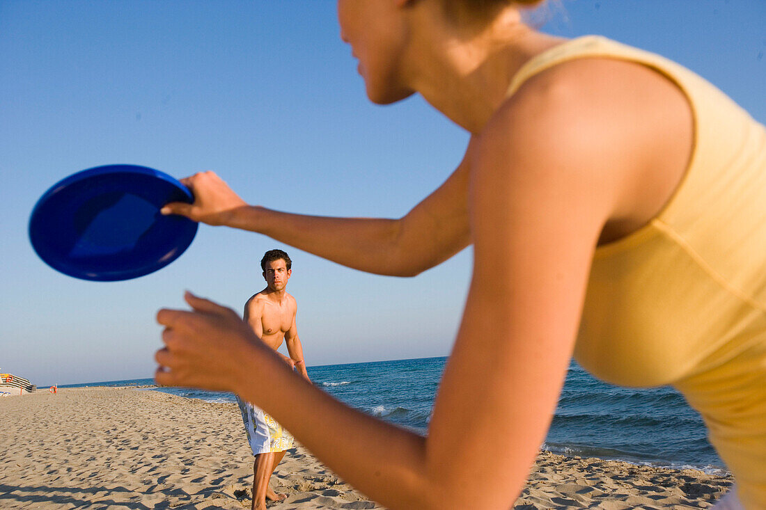 Junges Paar spielt Frisbee am Strand, Apulien, Italien