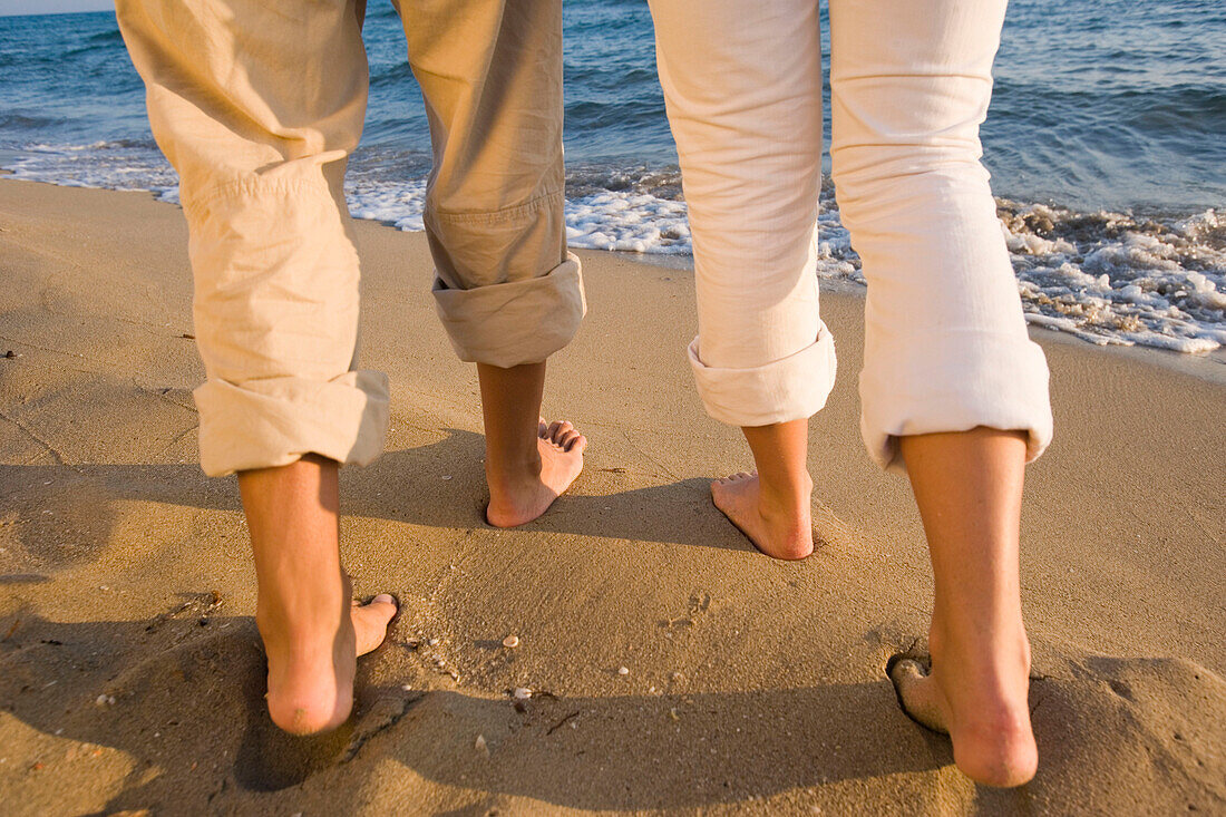 Junges Paar geht am Strand, nur Beine sichtbar, Apulien, Italien