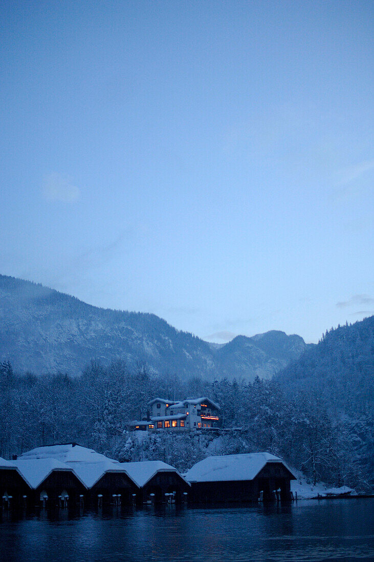 Ein Hotel und schneebedeckte Hütten am Seeufer, Königssee, Berchtesgardener Land, Bayern, Deutschland