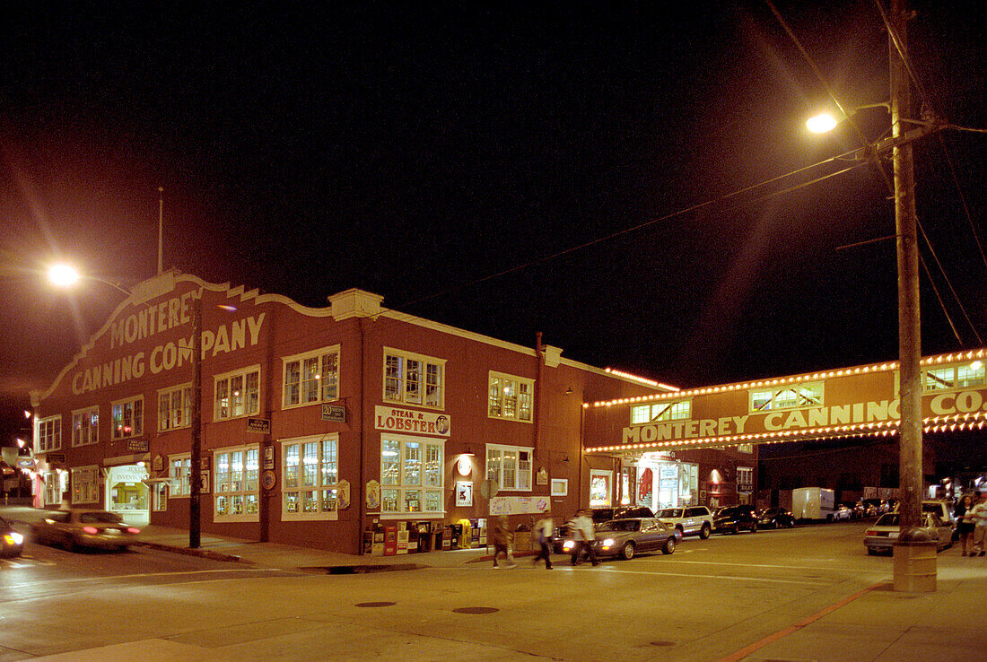 People crossing the street at night, Cannery Road, Monterey, California, USA