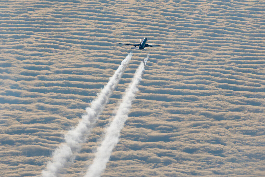 Aircraft with contrails overhead cloud layer
