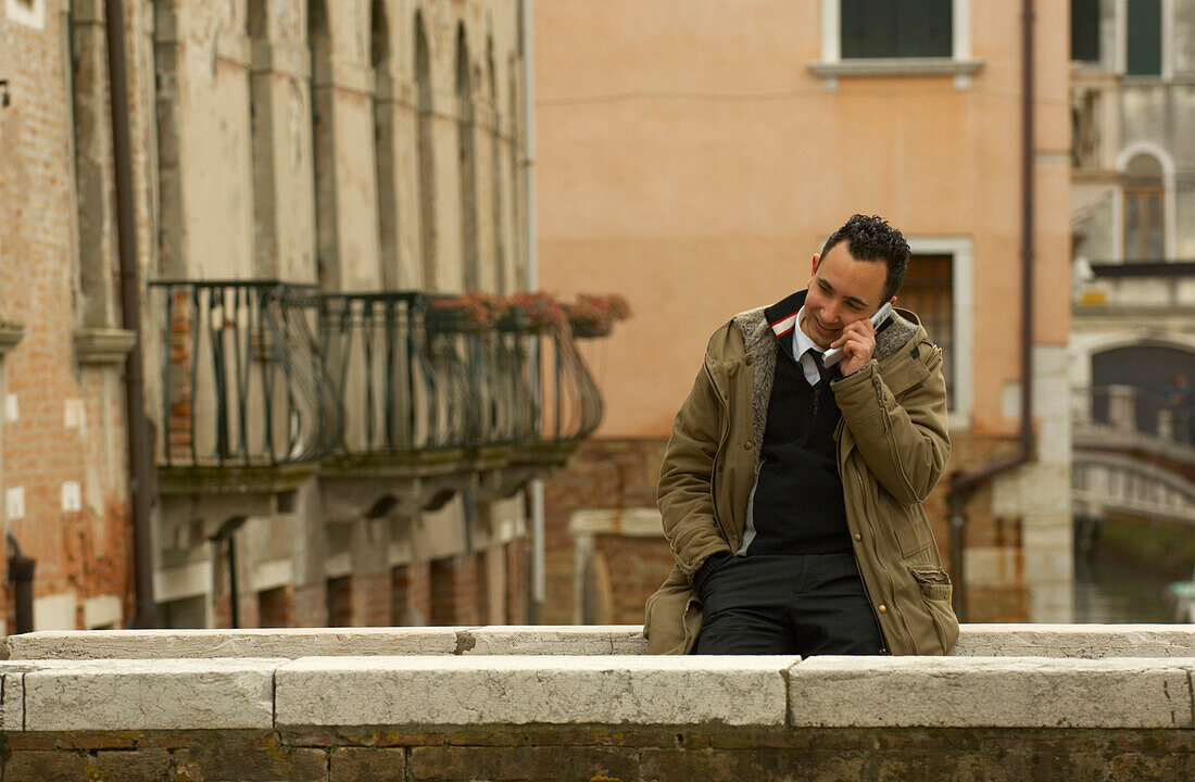 Mann mit Mobiltelefon auf einer Brücke in Venedig, Italien