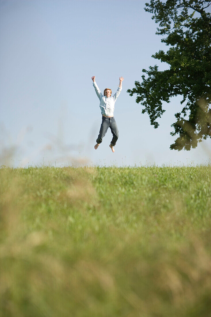 Junger springt in die Höhe auf einer Wiese