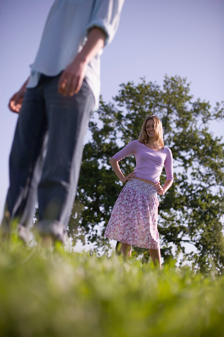 Young people standing on meadow, woman behind man
