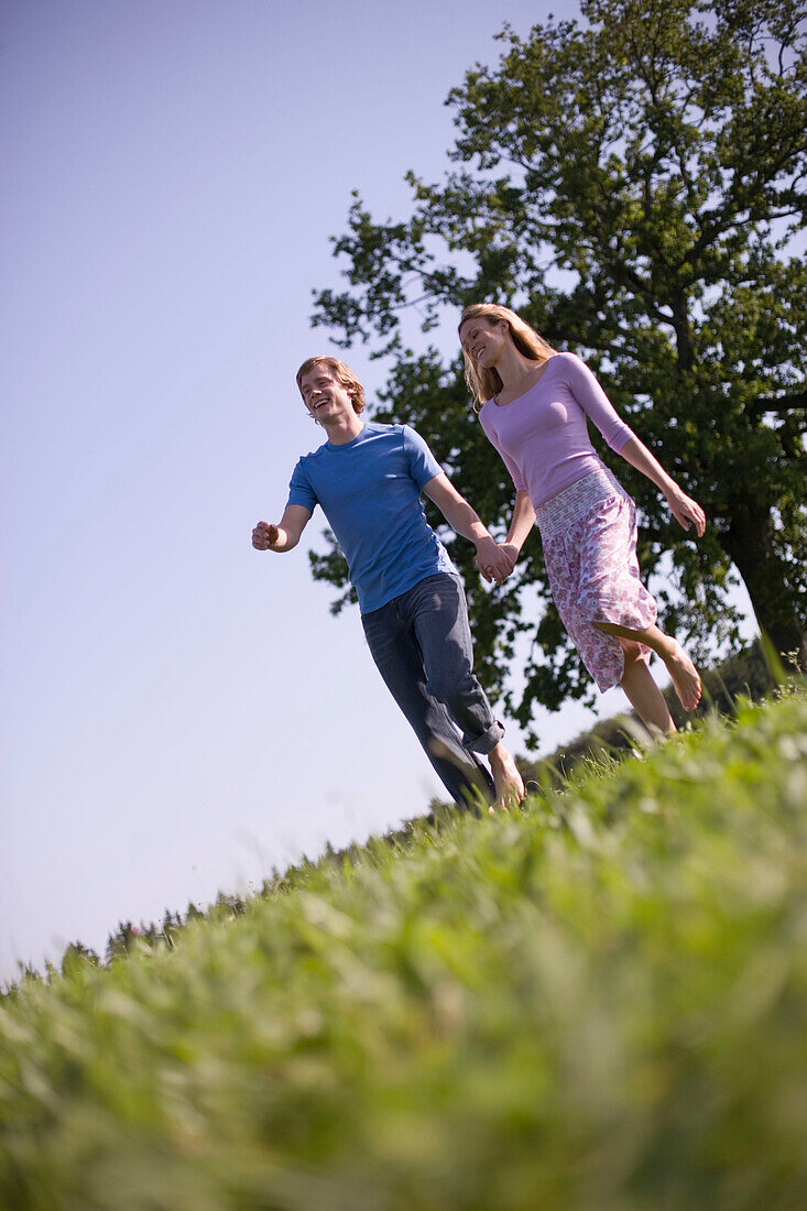 Couple walking down on meadow holding hands