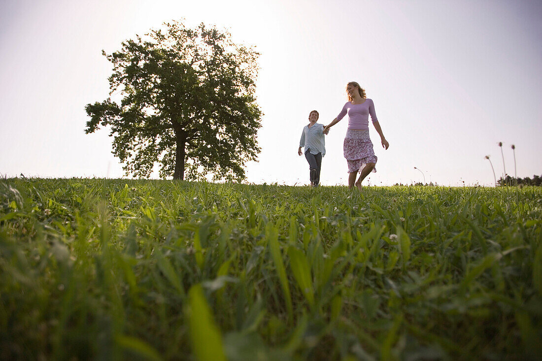 Couple running on meadow, hand in hand