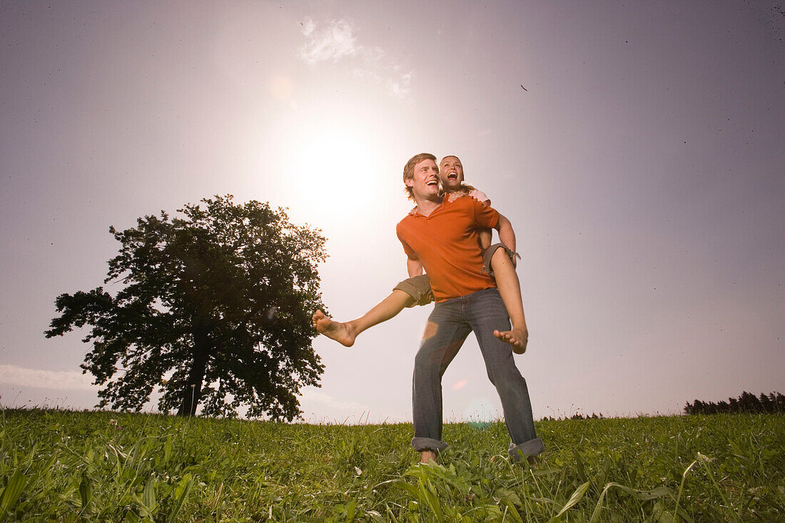 Man giving woman piggyback ride on grass