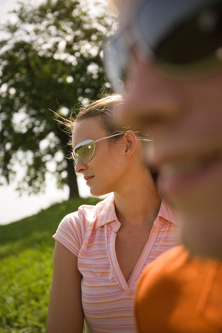 Two young people on meadow, both wearing sunglasses, close-up