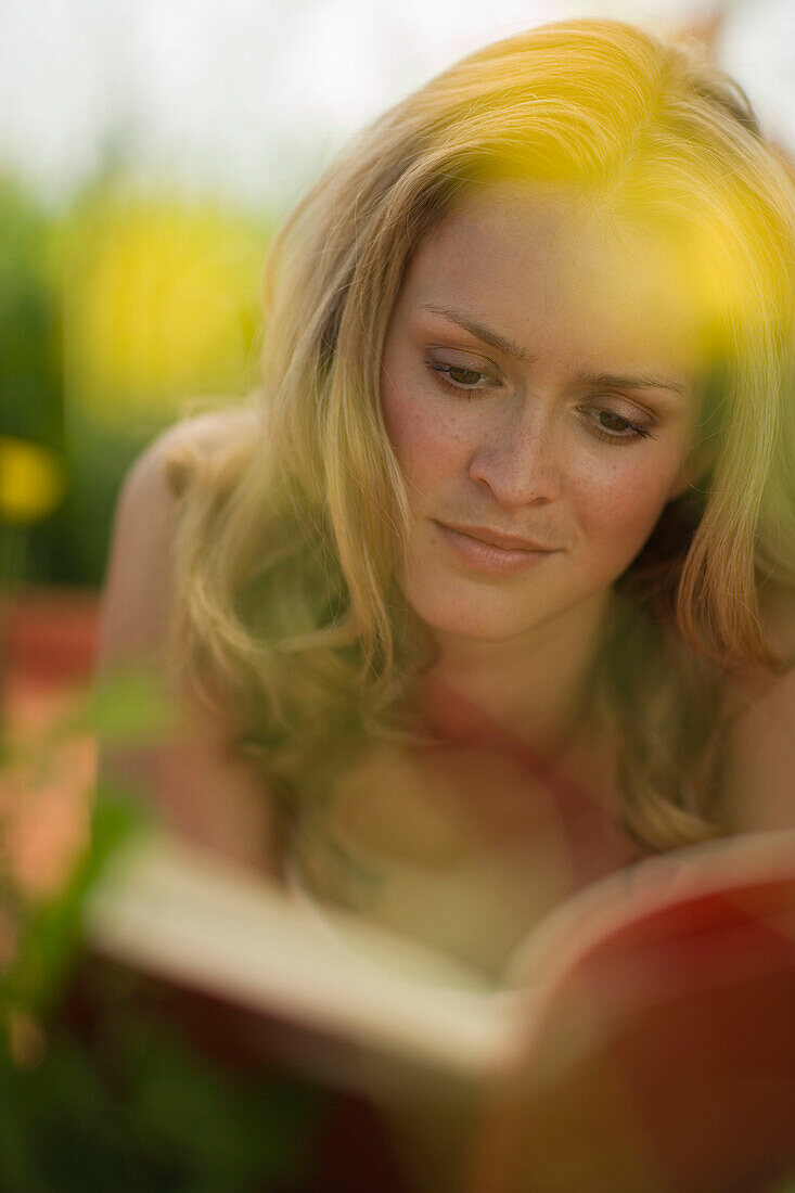 Young woman lying on meadow and reading book