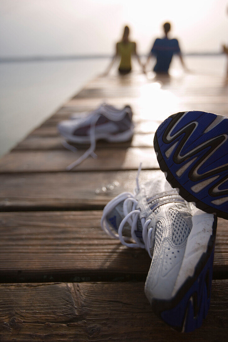 Zwei Personen sitzen auf Holzsteg, nach dem Joggen