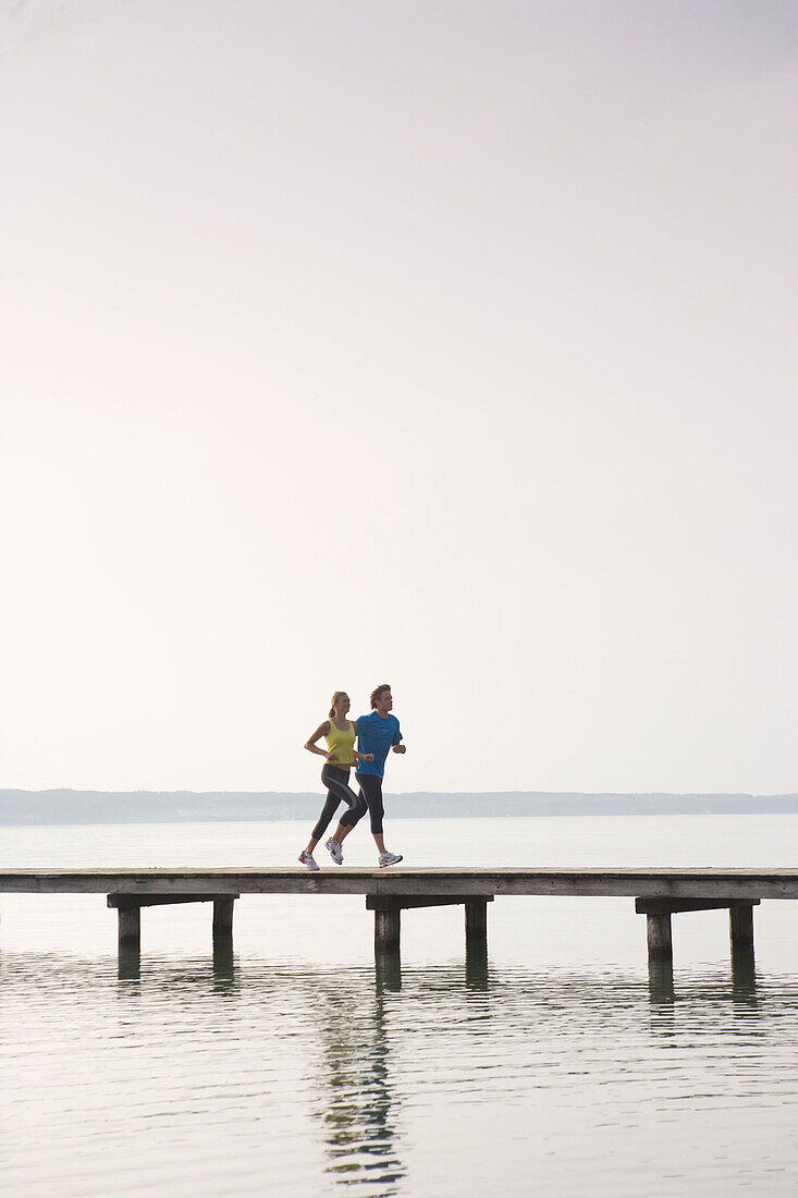 Zwei Personnen joggen auf Holzsteg