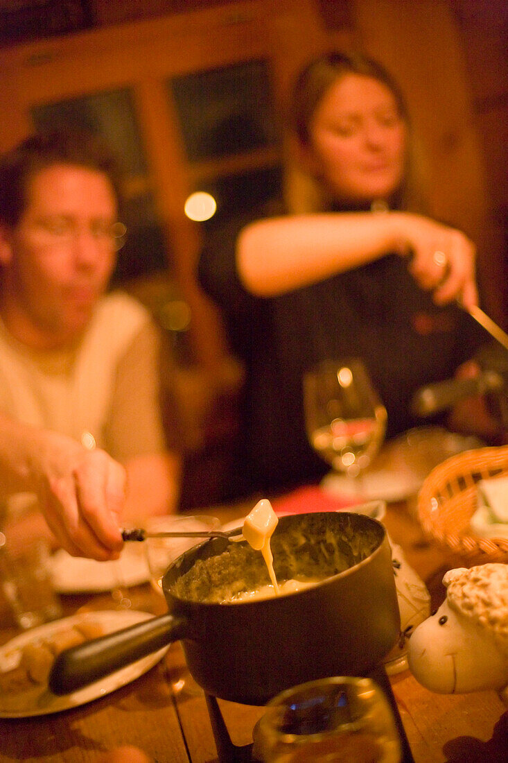 People having a cheese fondue, Fondue Hut of the Restaurant and Hotel Hohnegg, Saas-Fee, Valais, Switzerland