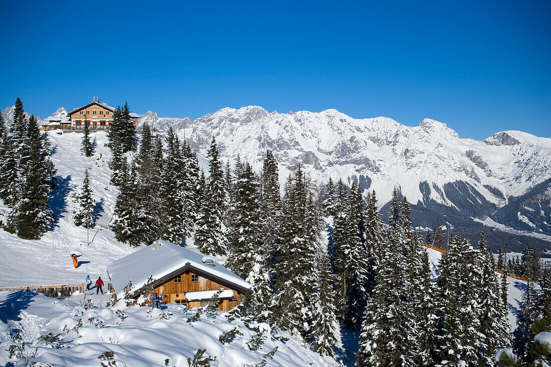 View to snowy hill with Hochwurzenalm and Hochwurzenhütte (1850 m), summit of the Dachsteinregion at horizon, Hochwurzen, Schladming, Ski Amade, Styria, Austria