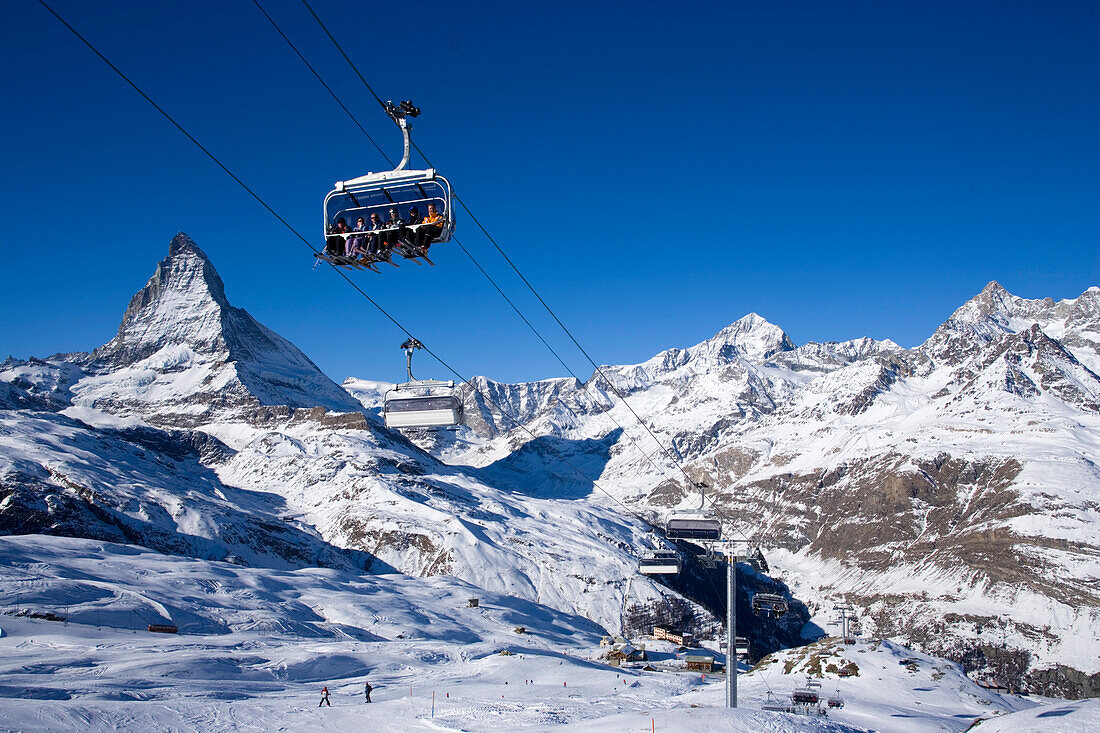 Skiers sitting on a ski lift, Matterhorn (4478 m) in background, Zermatt, Valais, Switzerland