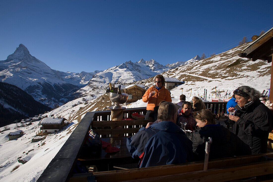 Group of people sitting on terrace of Restaurant Paradies (2540 m) and drinking champagne, Matterhorn (4478 m) in background, Findeln, Zermatt, Valais, Switzerland
