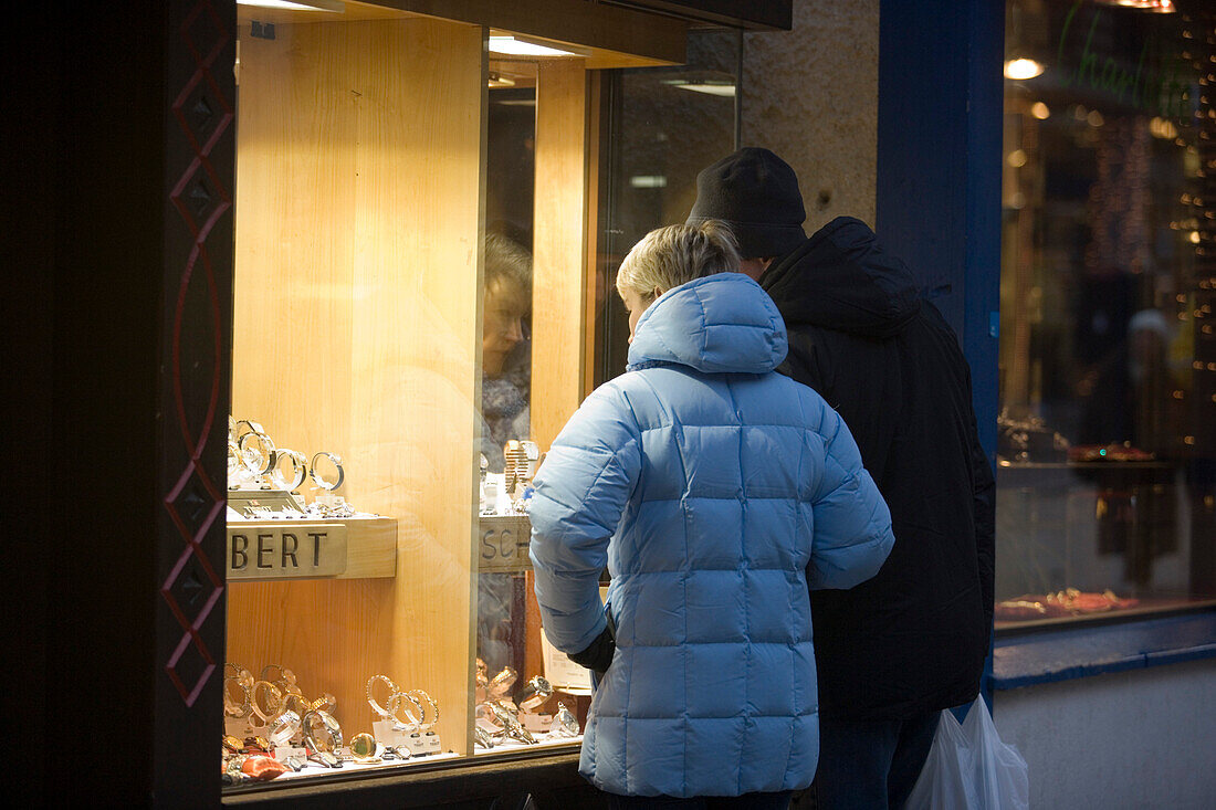 Couple standing in front of a shop window of a jeweller, Bahnhofstrasse, Zermatt, Valais, Switzerland