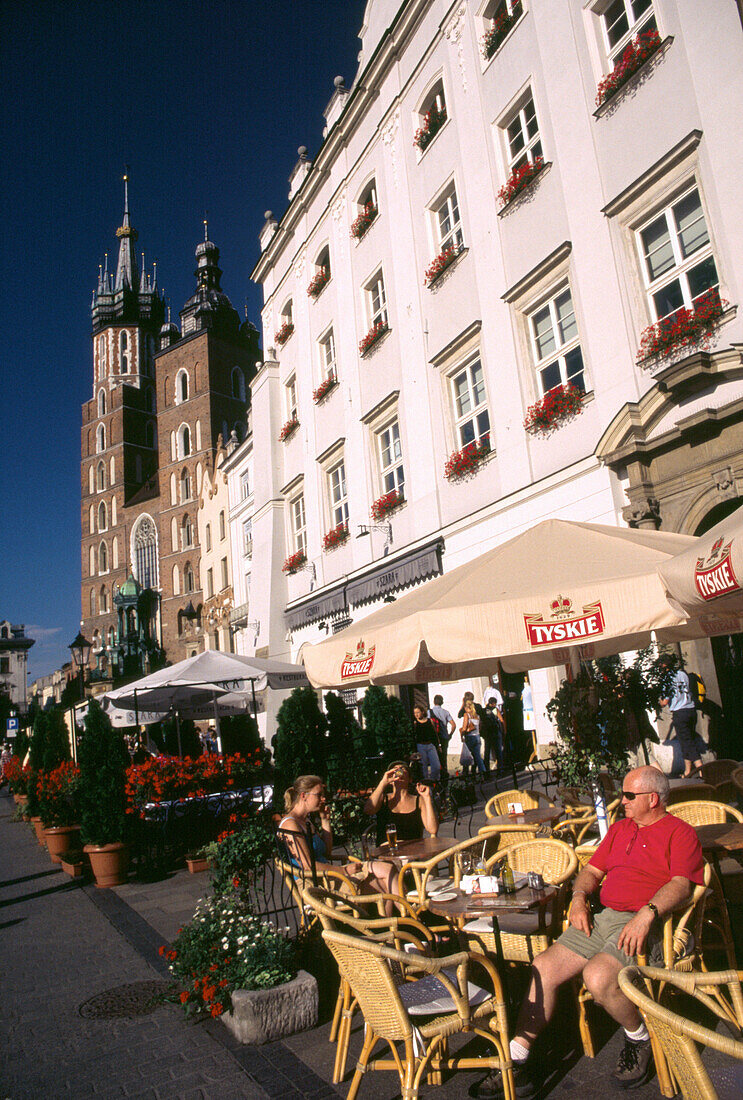 Tourists in cafe near the Church of Virgin Mary, Market Square in Cracow, Poland