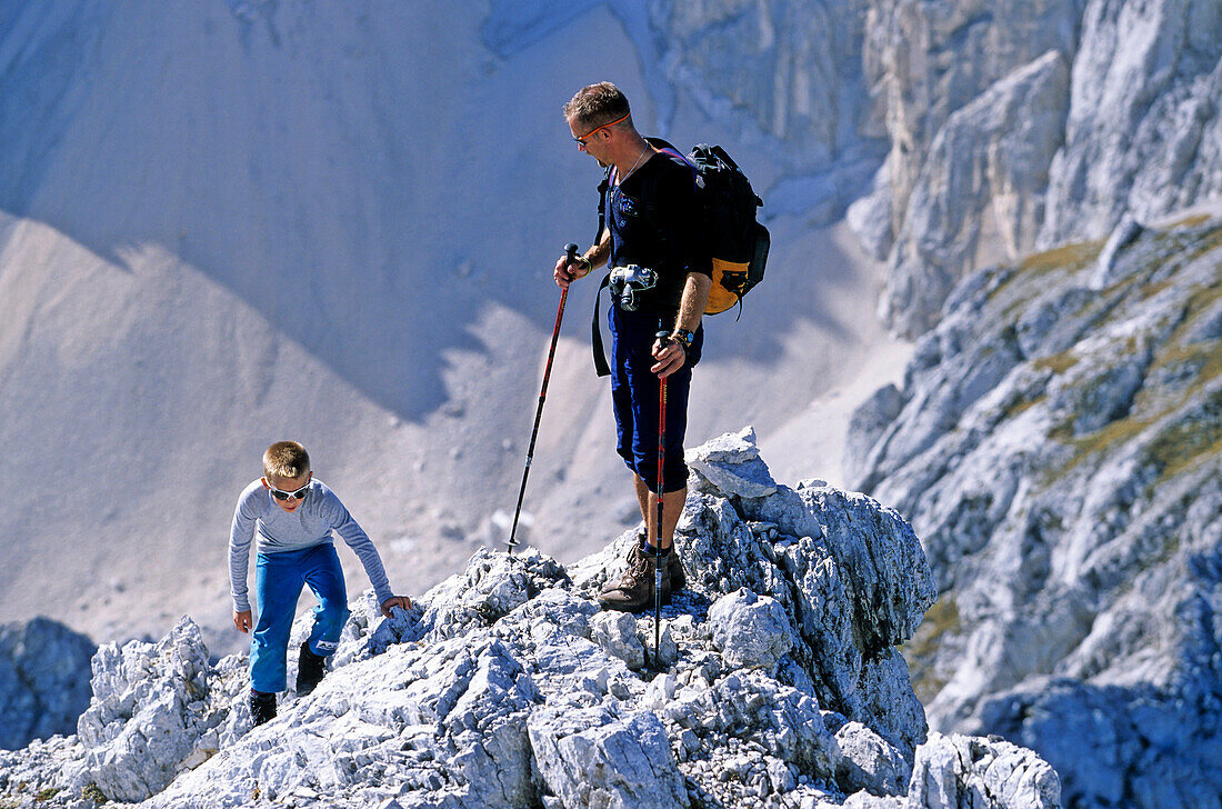 Vater und Sohn kraxeln zur Spitze eines felsigen Gipfels. Gipfel des Amfiteaters, Triglav Nationalpark, Julische Alpen, Slowenien, Alpen,.