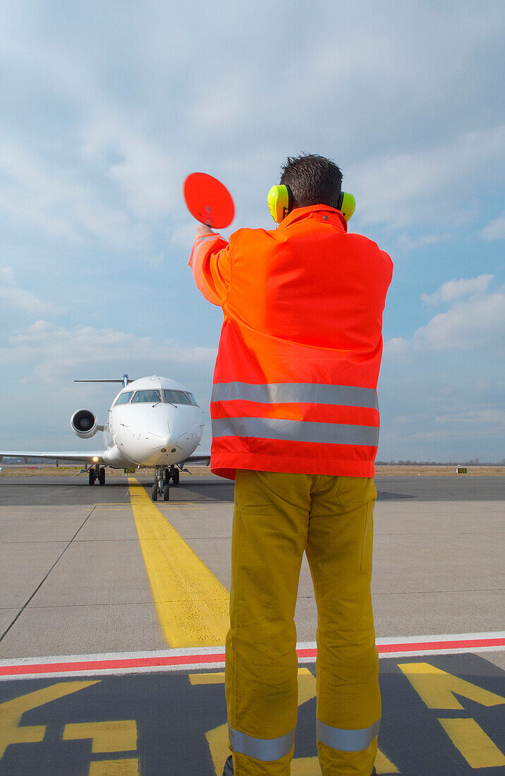 Airport ground crew signaling to aircraft, Airport Düsseldorf, North Rine-Westphalia, Germany