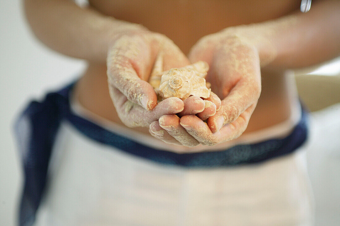 Sandy hands holding shells