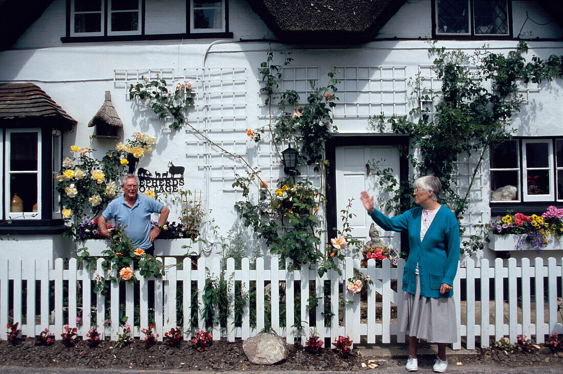 Neighbours greeting each other in front of a nicely restored cottage near Swampton, Hampshire, England
