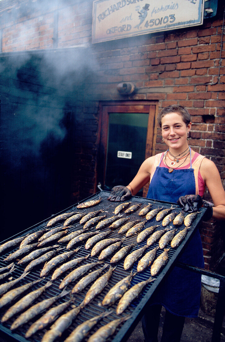 Woman presenting smoked kippers, Orford, Suffolk, England