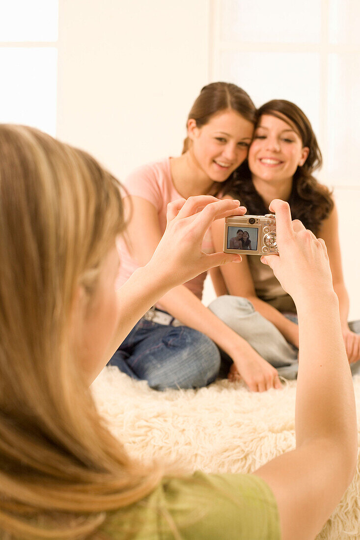 Teenage girl (14-16) taking photo of two other girls
