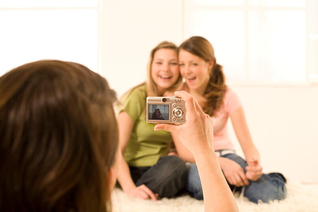 Teenage girl (14-16) taking photo of two other girls