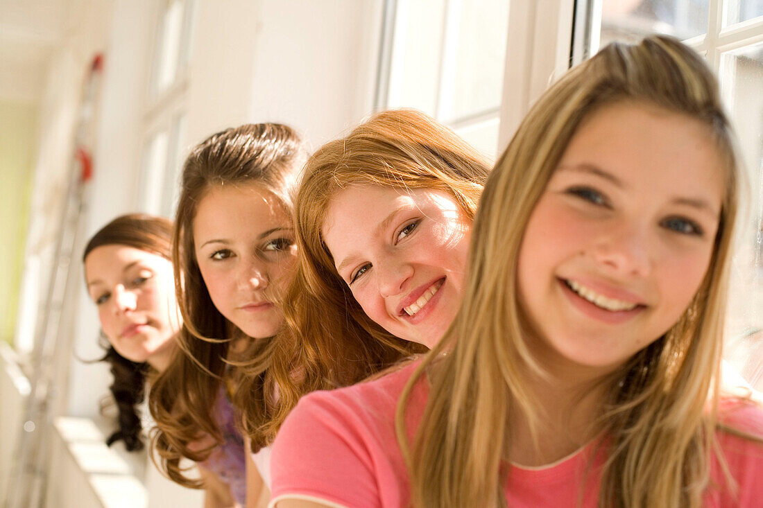 Teenage girls (14-16) sitting on window sill