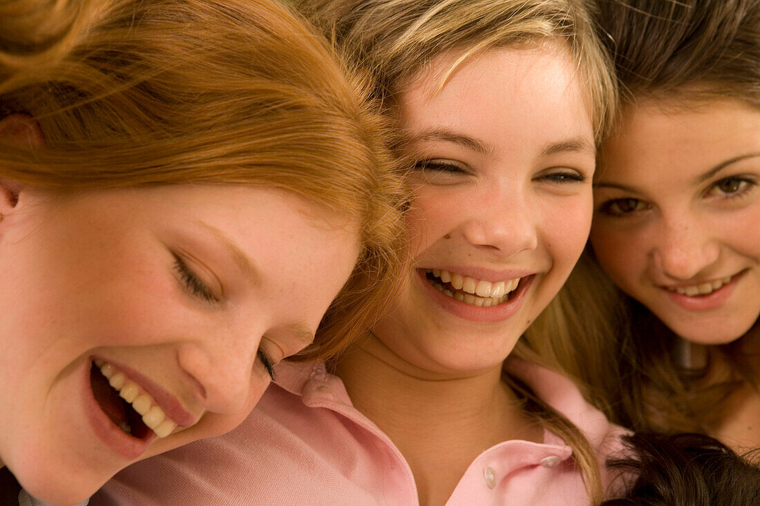 Three teenage girls (14-16) snuggling together on bed, close-up