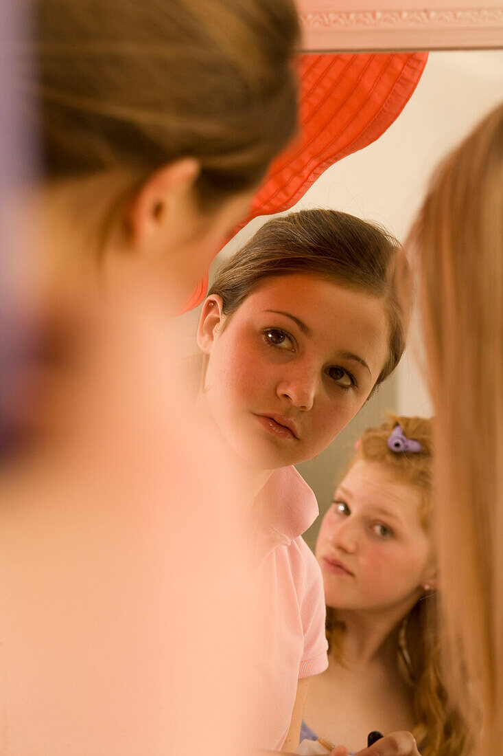 Teenage girl (14-16) applying make-up in mirror, sideview