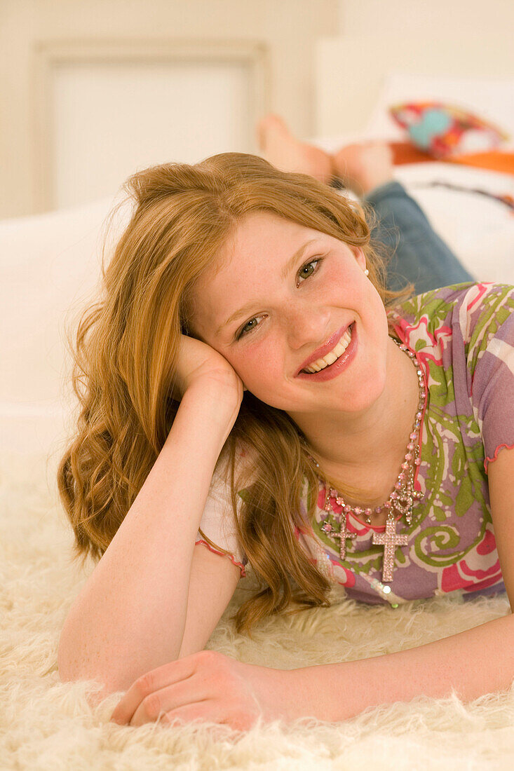 Teenager, Mädchen (14-16) liegt auf Felldecke, lächelt