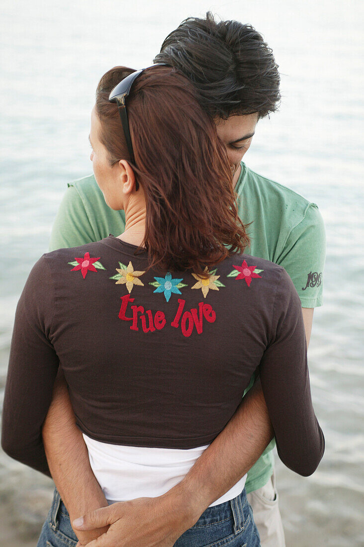 Couple in clothes embracing on the beach, portrait