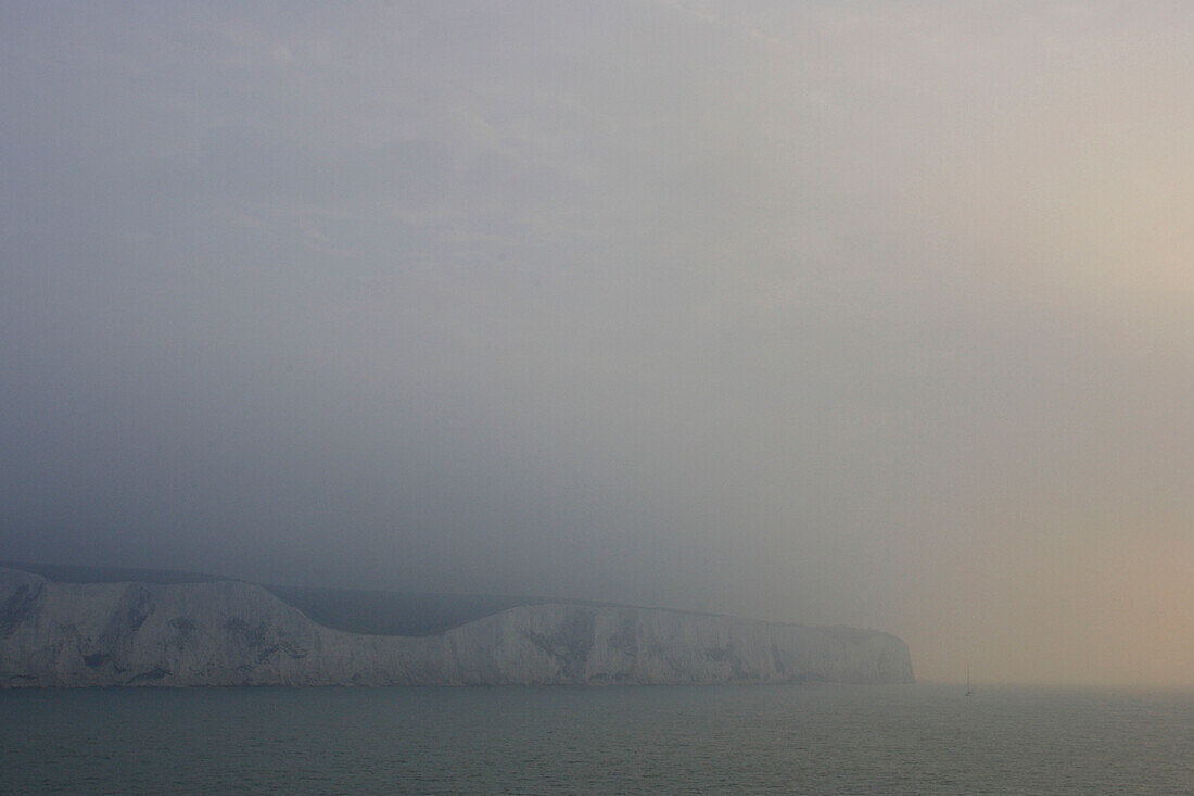 Limestone cliffs at the English Channel on a foggy morning, view from cruise ship MS Delphin Renaissance