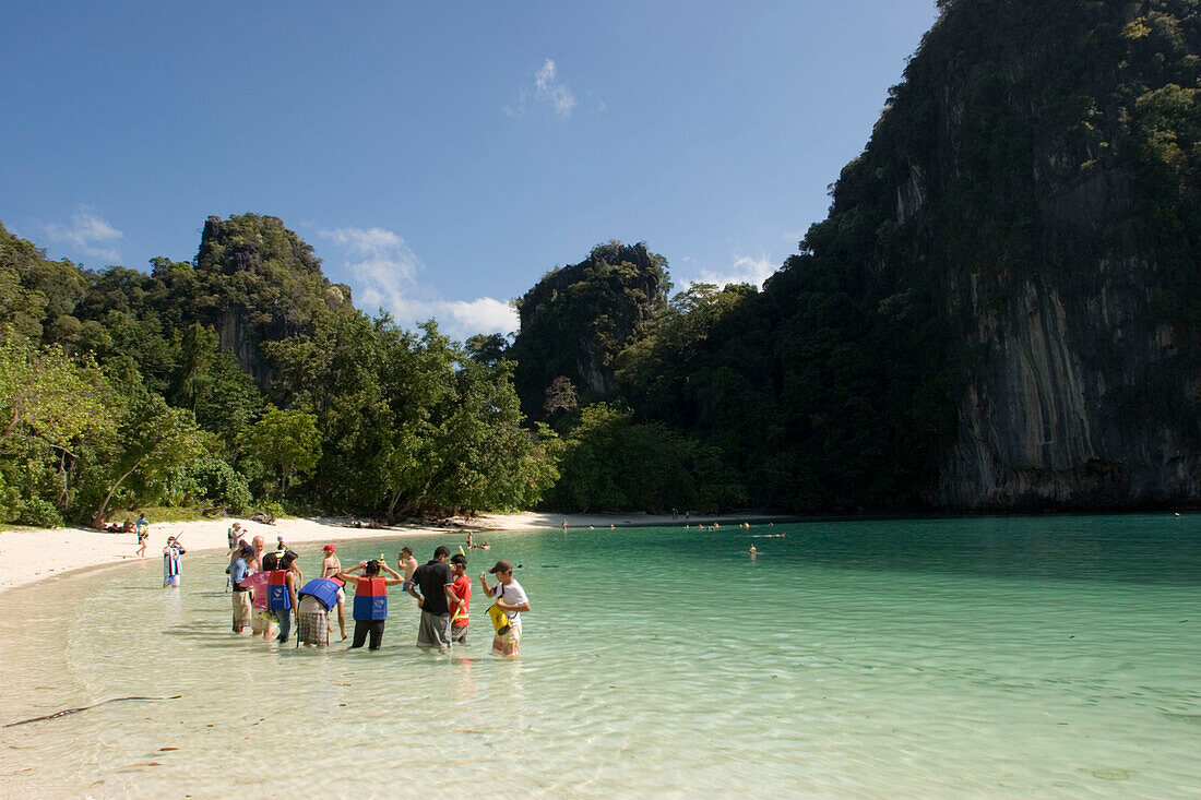Group of tourists standing in shallow water at beach of Koh Hong, Hong Island, Krabi, Thailand
