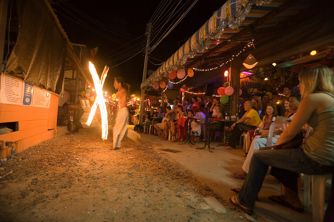 Tourists sitting in a beach bar, man juggling fire pois, Ko Phi Phi Don, Ko Phi Phi Island, Krabi, Thailand, after the tsunami