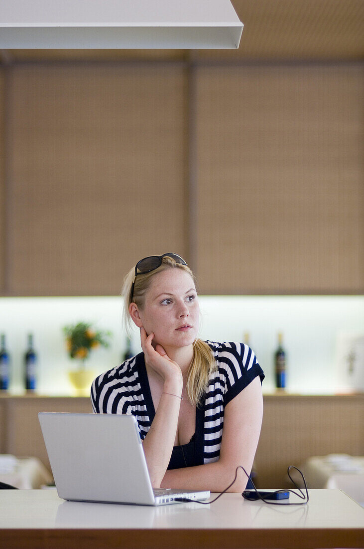 Woman sitting in restaurant, laptop on table