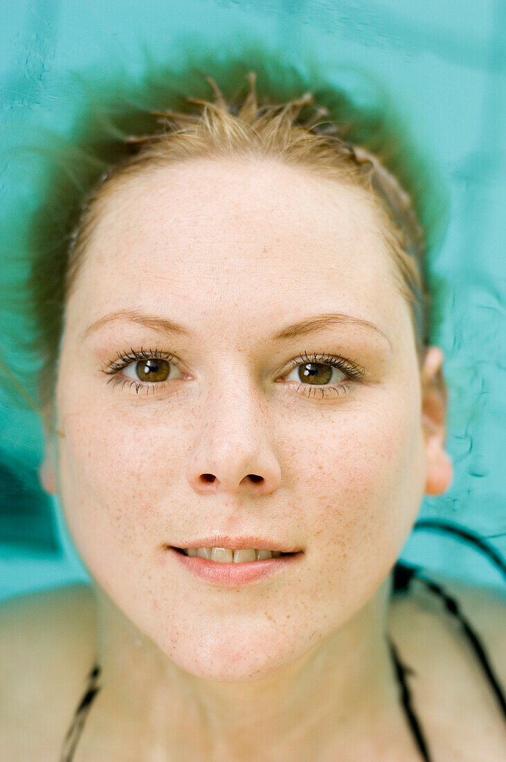 Woman in swimming pool, head lying on water, Germany