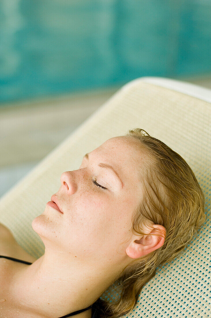 Woman relaxing on deckchair by pool, Germany