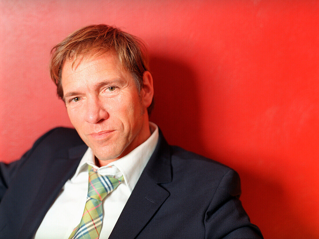 Buisness man leaning on red wall, portrait