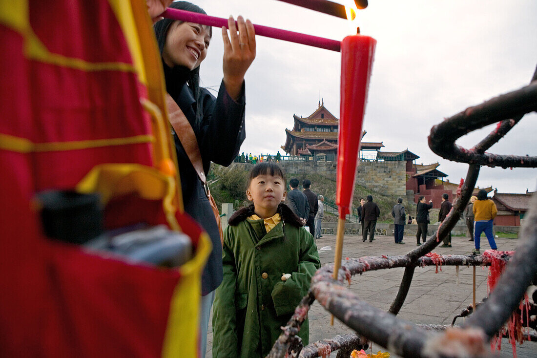Frau und Kind zünden morgens eine Kerze an, Emei Shan Gebirge, Provinz Sichuan, China, Asien