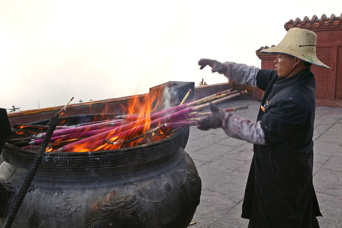 Mann verbrennt Räucherstäbe in einem Kessel, Emei Shan Gebirge, Provinz Sichuan, China, Asien